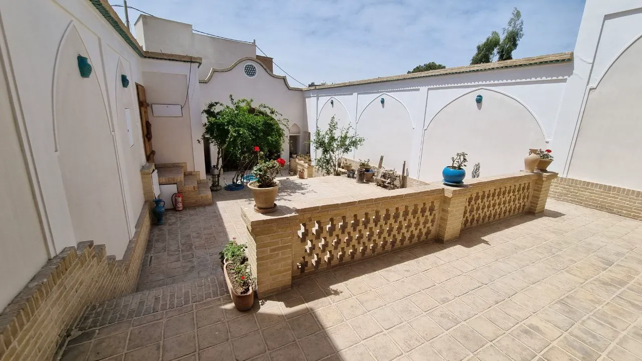 حیاط سرای ملک با باغچه و دیوارهای آجری