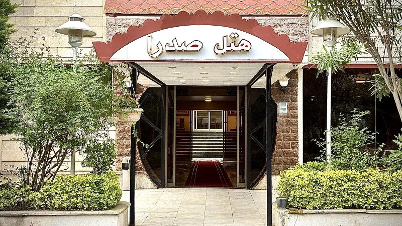 ورودی هتل صدرا با سردر و باغچه‌های سبز