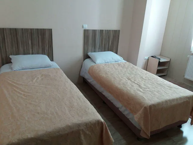 دو تخت یک‌نفره با روتختی کرم در هتل آتا