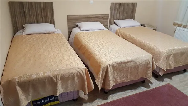 سه تخت یک‌نفره در اتاق هتل آتا