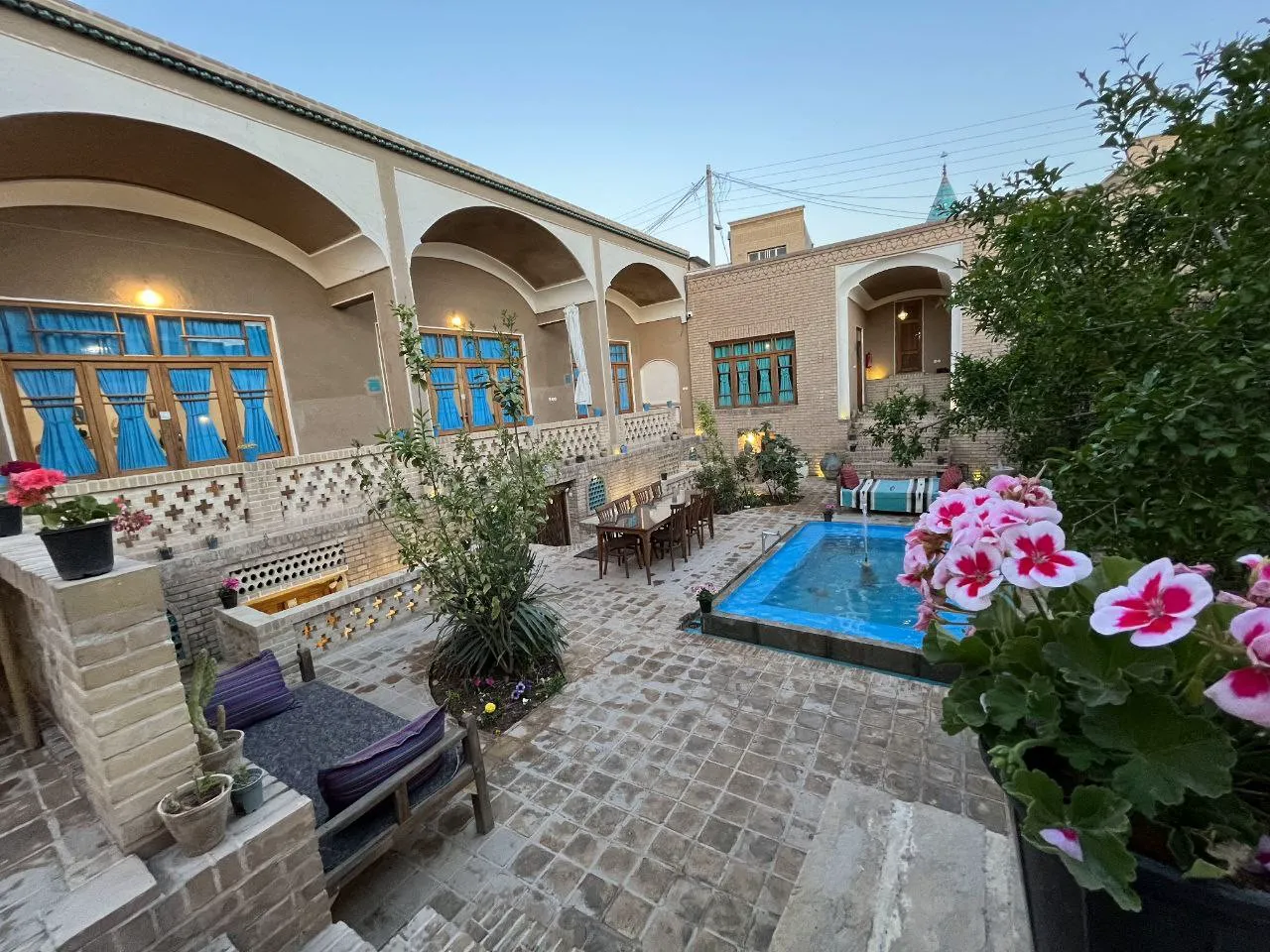 حوض و گل‌های رنگارنگ در حیاط سرای آقا محمد