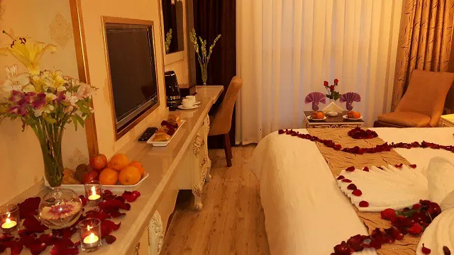 اتاق هتل بغدادی با تخت گلآراییشده و میز تلویزیون