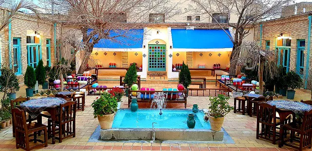 حیاط سرای هاتف با حوض مرکزی و تخت‌های سنتی