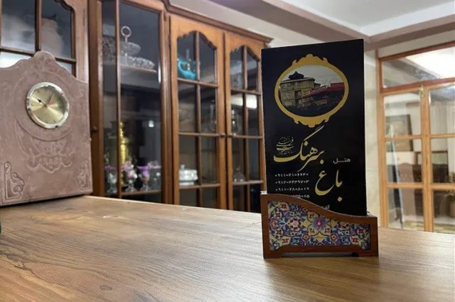 نشان و بروشور باغ سرهنگ روی میز چوبی