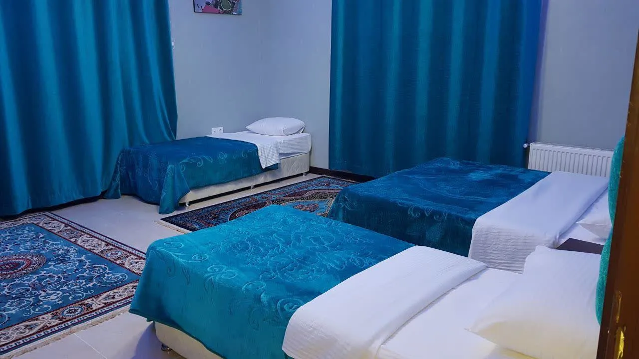 اتاق هتل نور با تخت‌های یک‌نفره و روتختی فیروزه‌ای