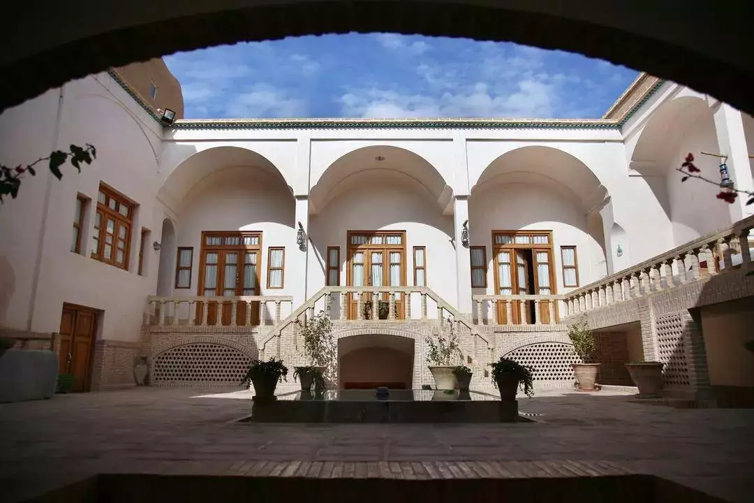 حیاط مرکزی کاشانه روشن با حوض و ایوان قوسی
