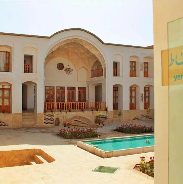 حیاط هتل فلاحتی با حوض و بنای قوسدار