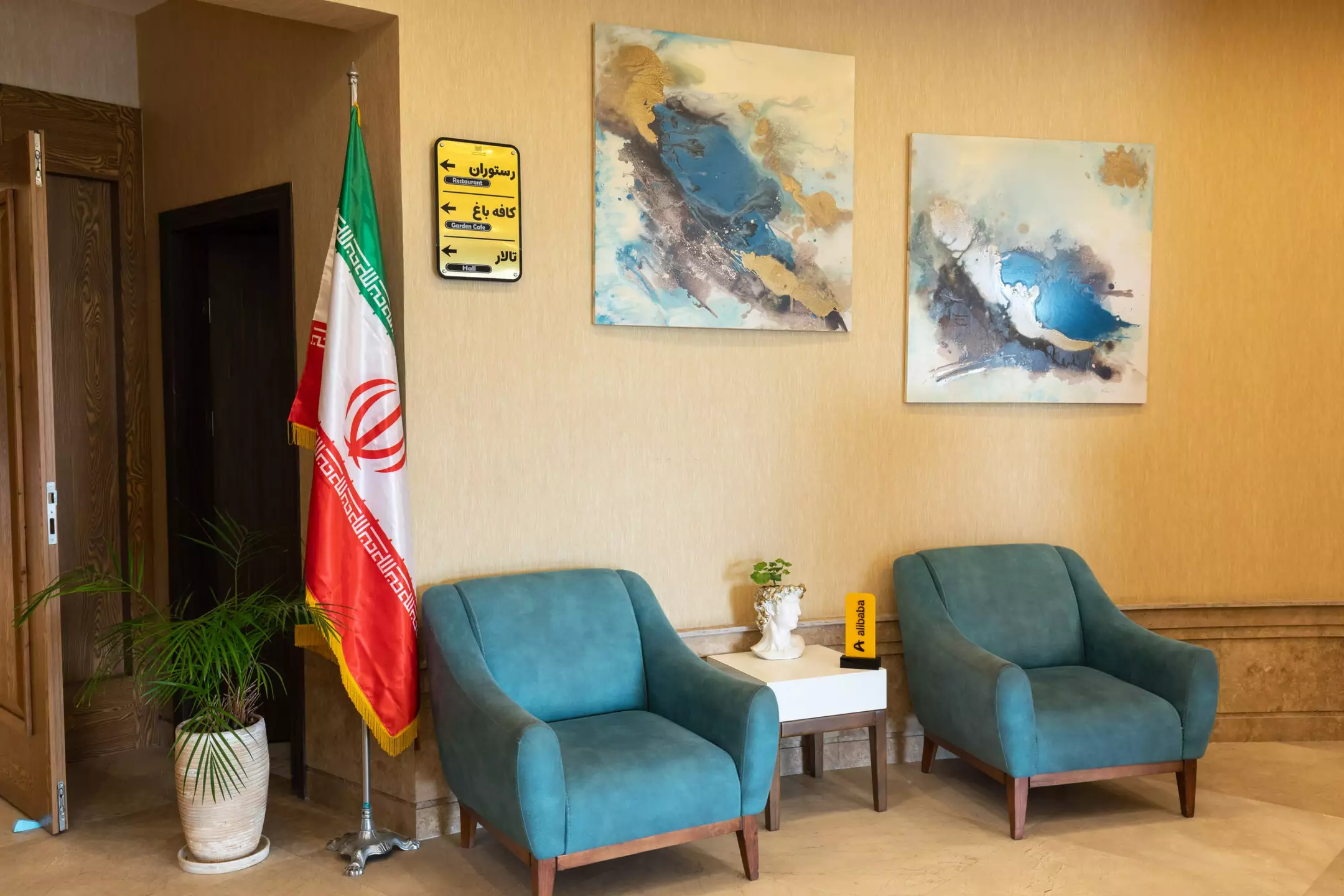 فضای نشیمن هتل شهرزاد با دو مبل آبی و پرچم ایران