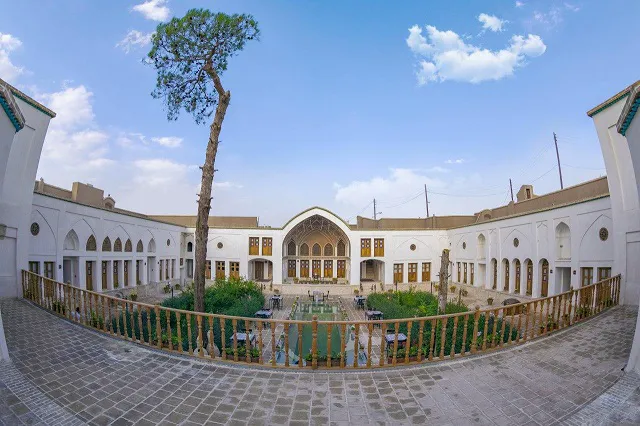 حیاط هتل کاسیان با ایوان قوسی و درخت