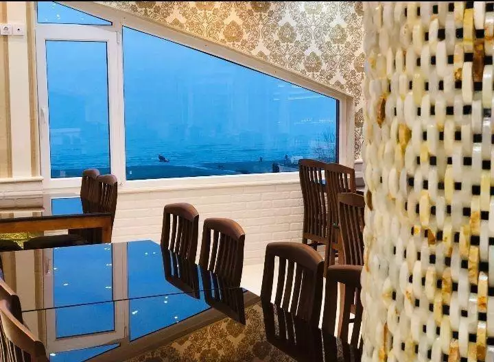 میز و صندلی‌های کنار پنجره رو به دریا در هتل آرکا