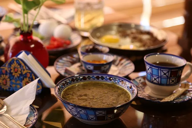 کاسه‌های غذای ایرانی و فنجان چای در هتل انار