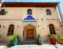 نمای آجری هتل سنتی درباری با ورودی چوبی