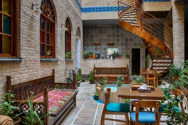 حیاط سنتی هتل سنتی درباری با حوض و تخت‌های چوبی