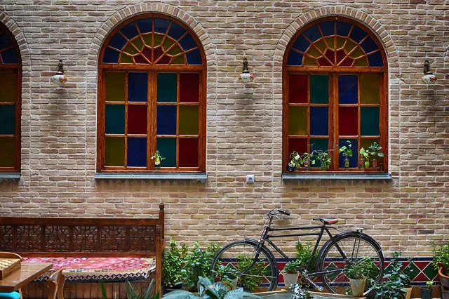 پنجره‌های رنگی و دوچرخه در حیاط سنتی درباری