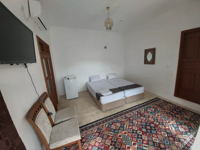 اتاق خواب عمارت بامگاه با تخت دونفره و فرش رنگارنگ