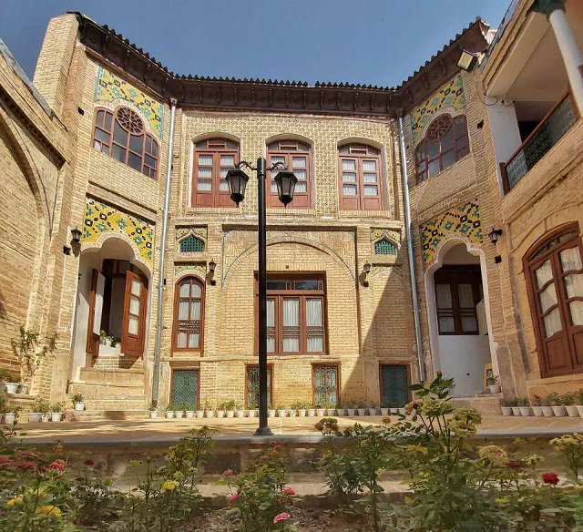 حیاط عمارت بامگاه با نمای آجری و باغچه
