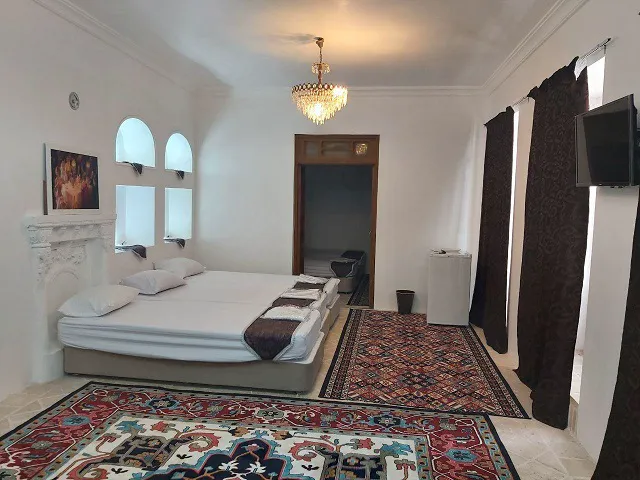اتاق عمارت بامگاه با تخت دونفره و فرش‌های ایرانی