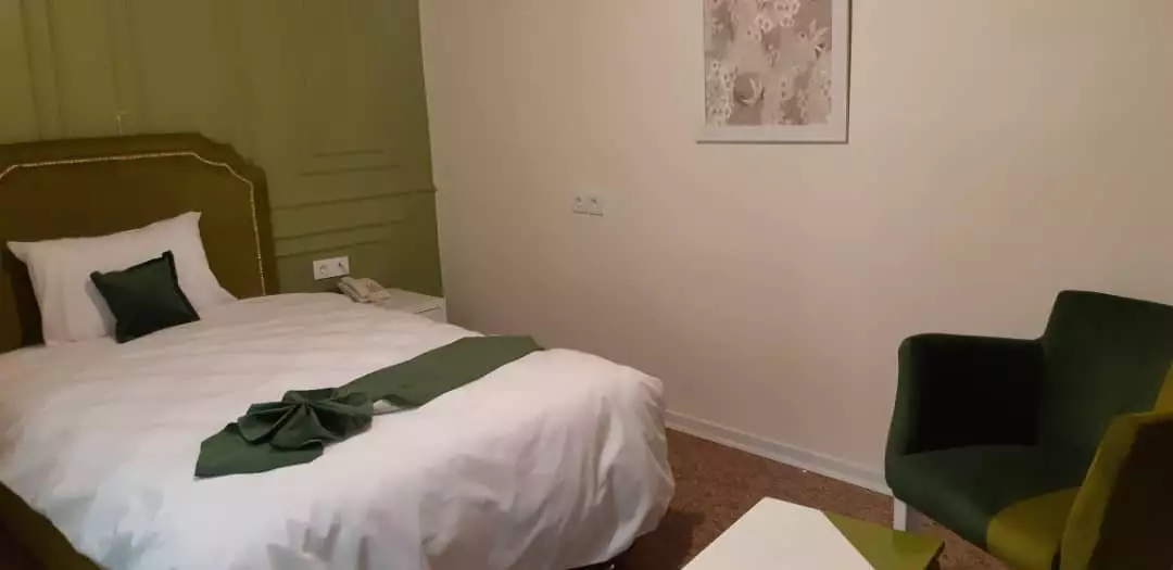 تخت دونفره سفید و صندلی سبز اتاق زاگرس