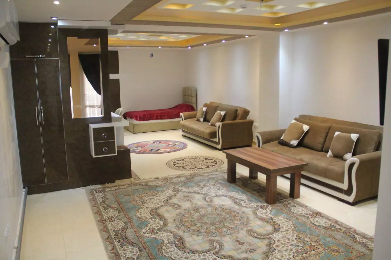 پذیرایی مبله اقامتگاه گیلبرتون با فرش و میز چوبی