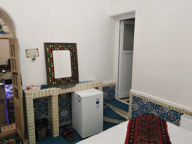 اتاق هتل شهباز با آینه قاب‌رنگی و کاشی سنتی