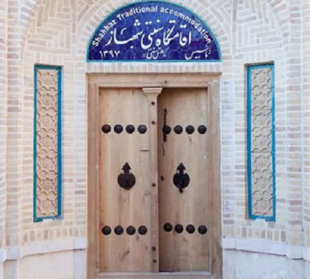 در چوبی ورودی اقامتگاه شهباز با کوبه‌های فلزی