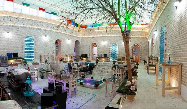 حیاط مرکزی هتل شهباز با درخت و تخت‌های نشیمن