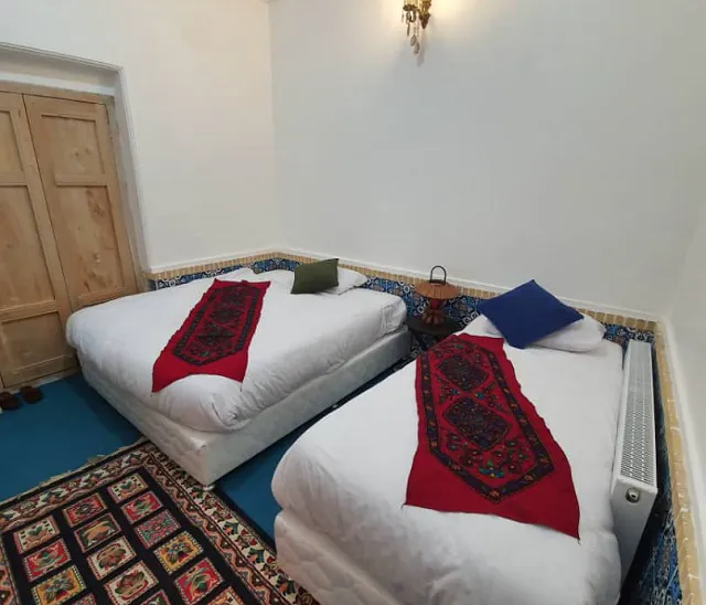دو تخت با رومیزی‌های سنتی در اتاق هتل شهباز