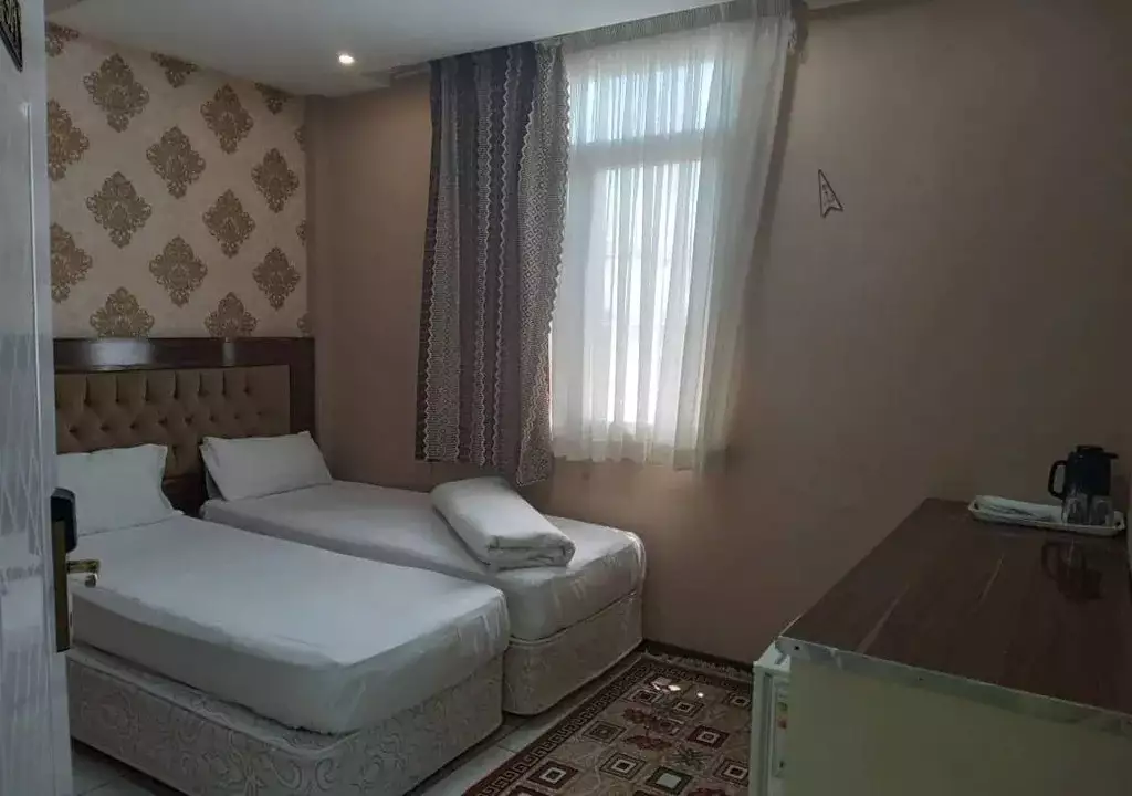 دو تخت یک‌نفره کنار پنجره اتاق هتل هرمس