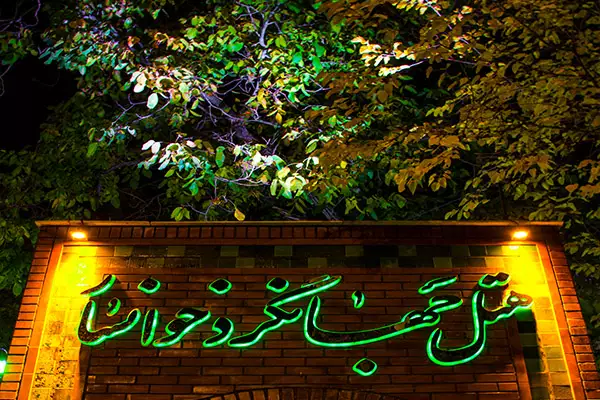 تابلوی نئونی نام هتل جهانگرد در میان درختان