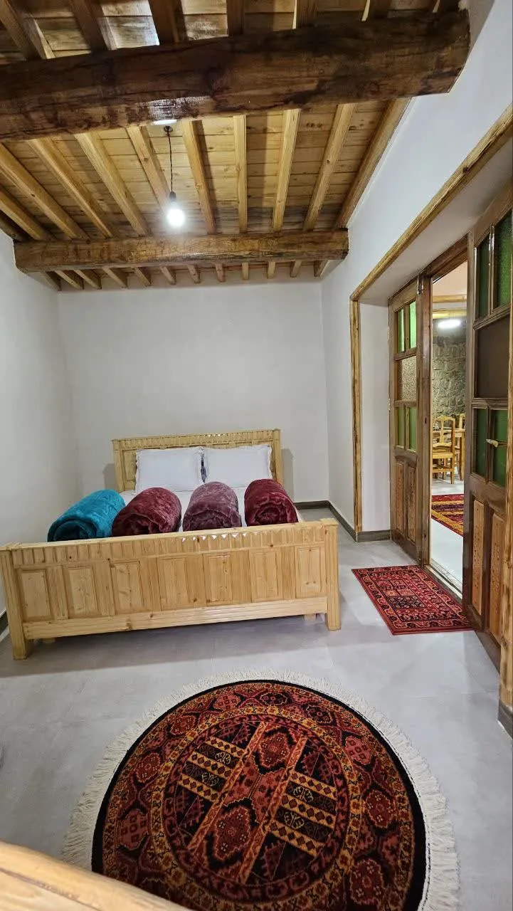 ماسوله؛ اتاق خواب با تخت چوبی و قالیچه گرد