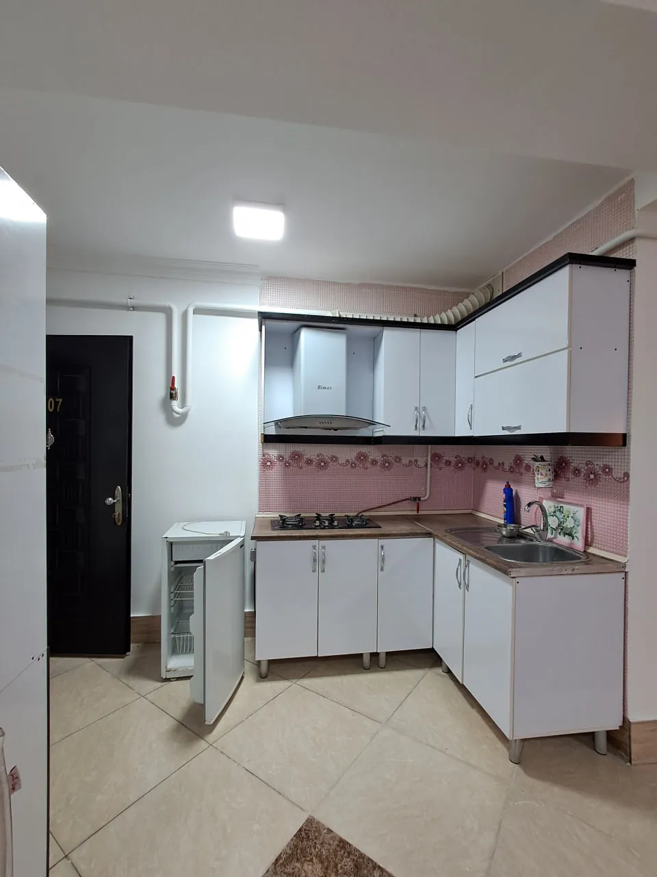 آشپزخانه برجیس با کابینتهای سفید و دیوار صورتی