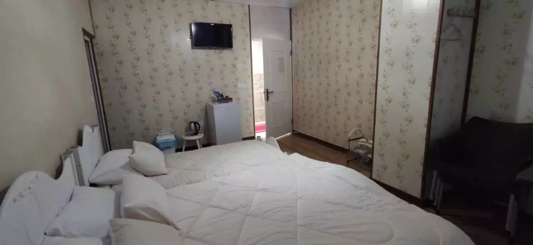 اتاق کندلوس با تخت سفید و کاغذدیواری گل‌دار