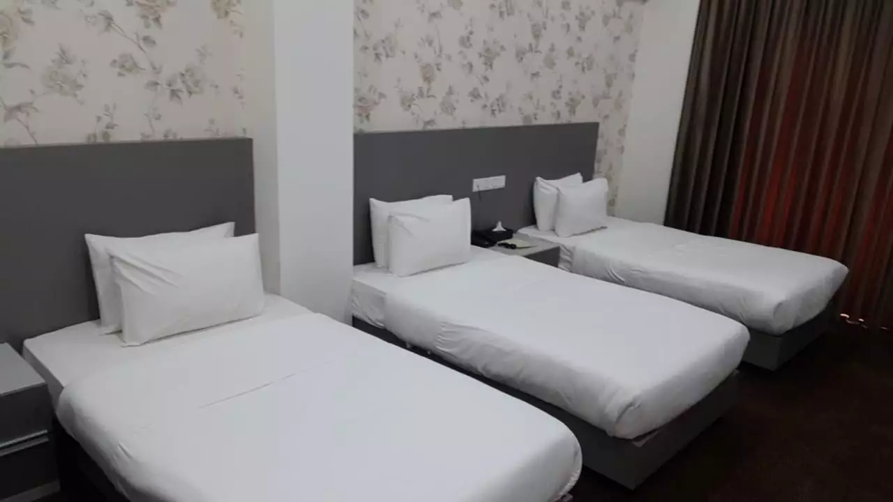 سه تخت یک‌نفره در اتاق هتل المقام
