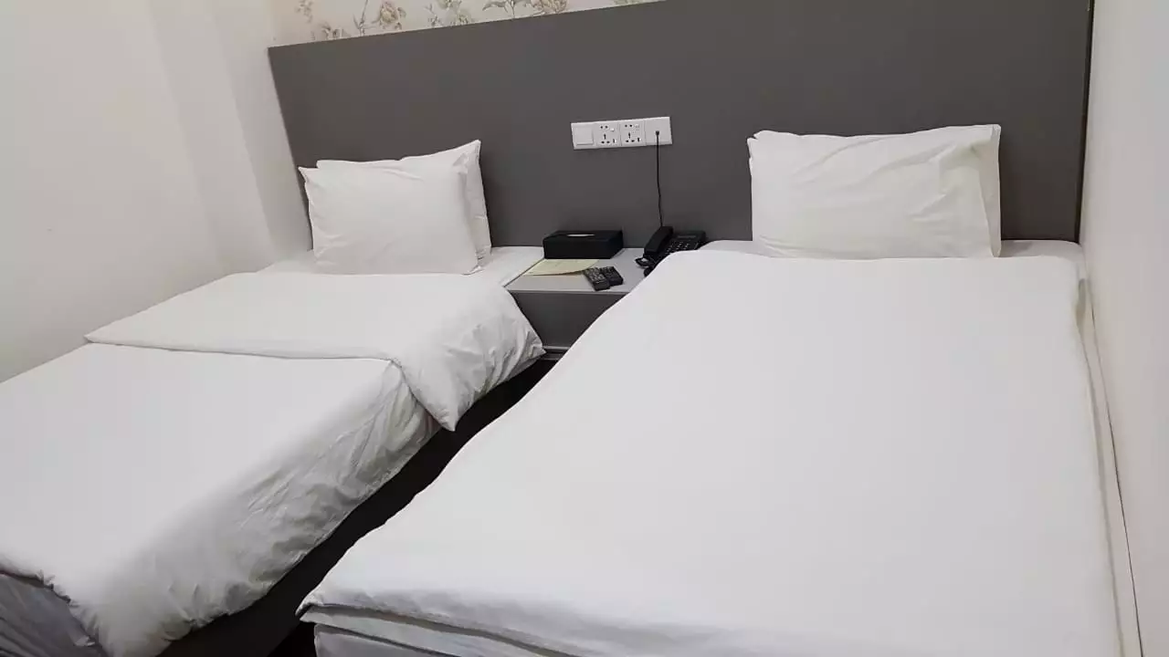 دو تخت یک‌نفره با ملحفه سفید در هتل المقام