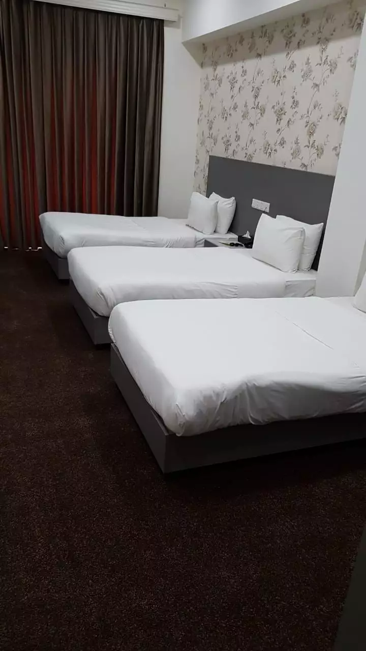 سه تخت یک‌نفره در اتاق هتل المقام